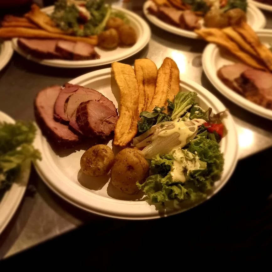 Platos con jamón y costillas ahumadas, tajadas de plátano maduro, papas y ensalada, servidos de noche.