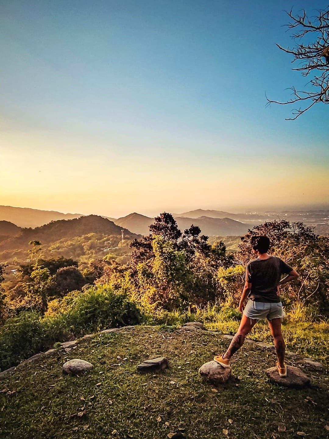 Una persona de pie sobre una roca del mirador privado mira las lomas de la Sierra Nevada encendidas por la luz dorada del atardecer.