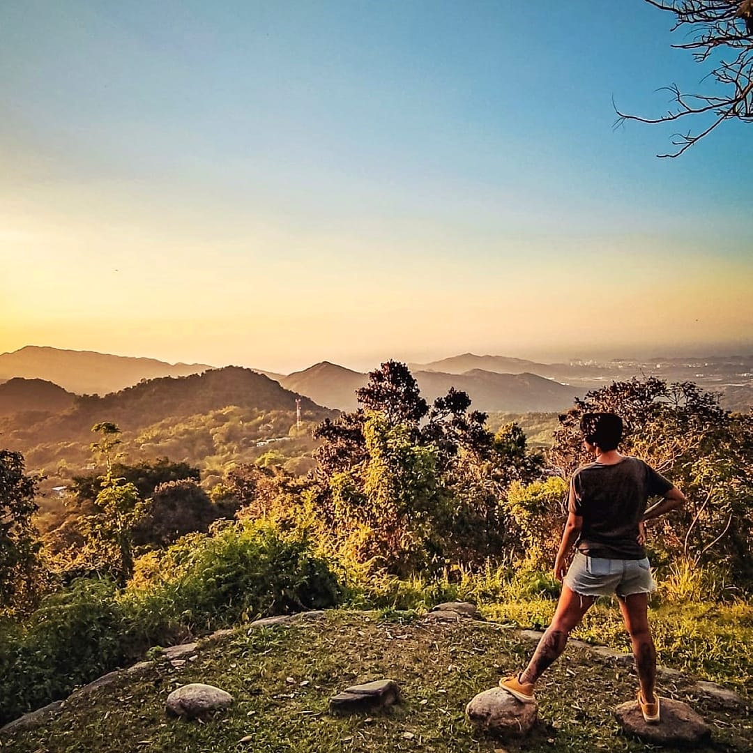 Una persona de pie sobre una roca del mirador privado mira las lomas de la Sierra Nevada encendidas por la luz dorada del atardecer.