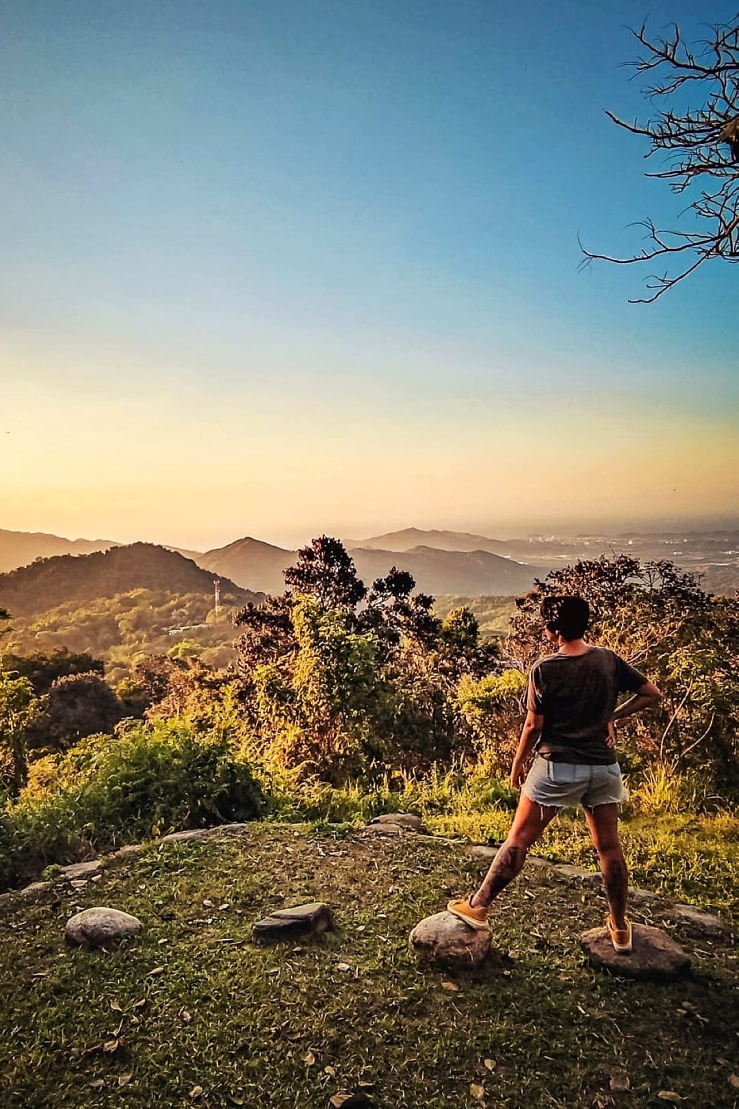 Una persona de pie sobre una roca del mirador privado mira las lomas de la Sierra Nevada encendidas por la luz dorada del atardecer.