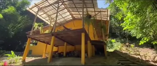La casa amarilla de Casa Maracuyá con su techo de guadua.