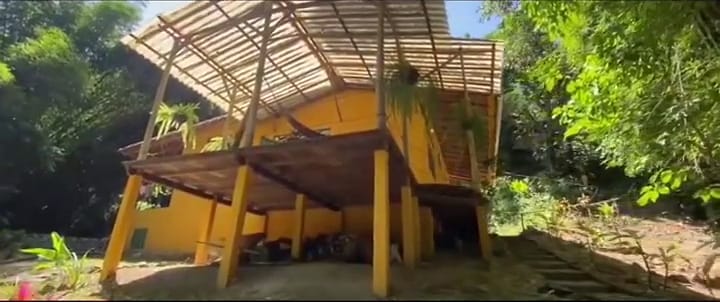 La casa amarilla de Casa Maracuyá con su techo de guadua.