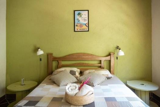 La doble de pared verde, con mesitas de noche redondas y cuadro.
