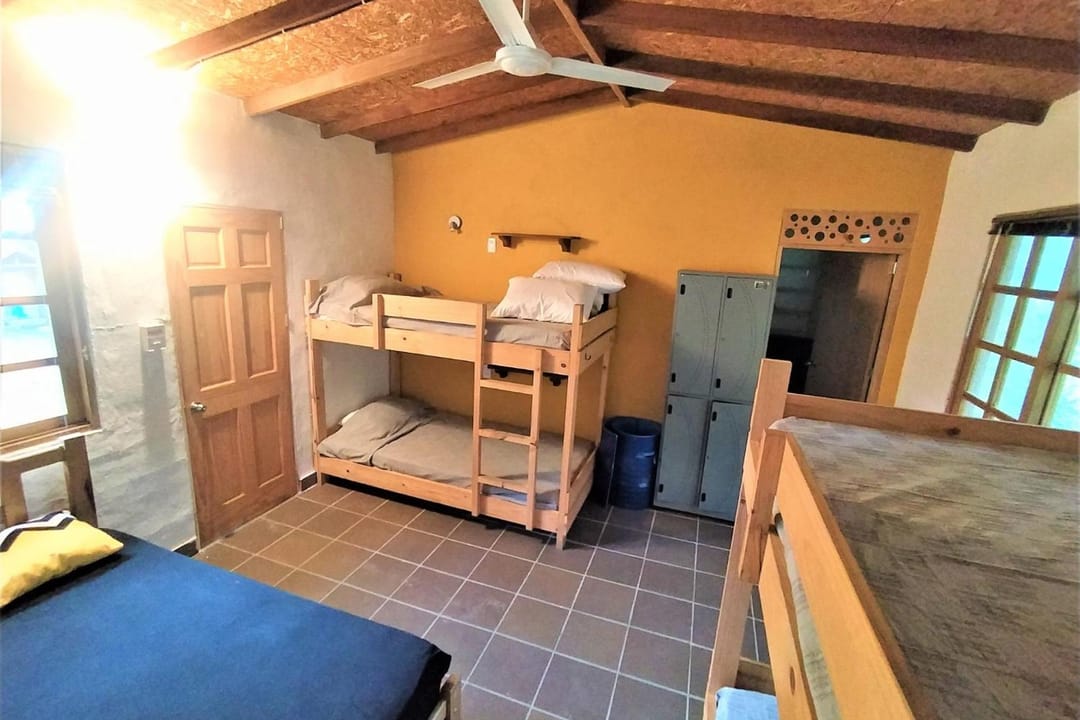 El dormitorio de Casa Quinta con luz de mañana: camarote, cama sencilla y ventanas de madera.