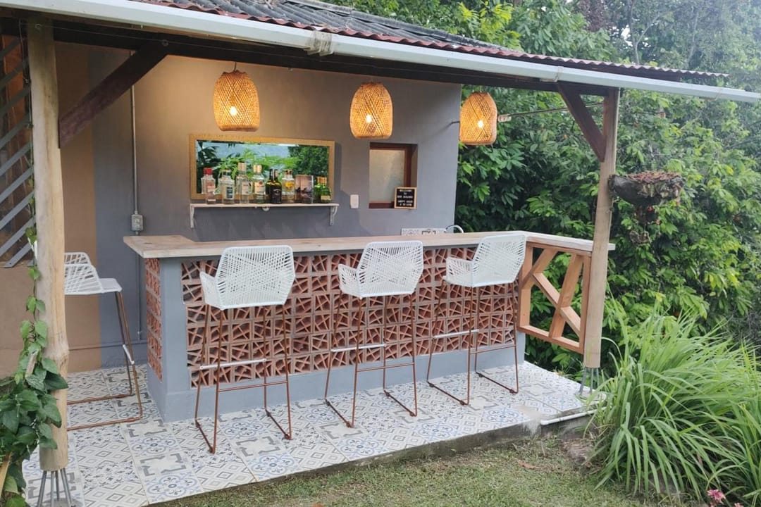 La barra de Bar Bolívar, con butacos, lámparas tejidas y plantas, de día.