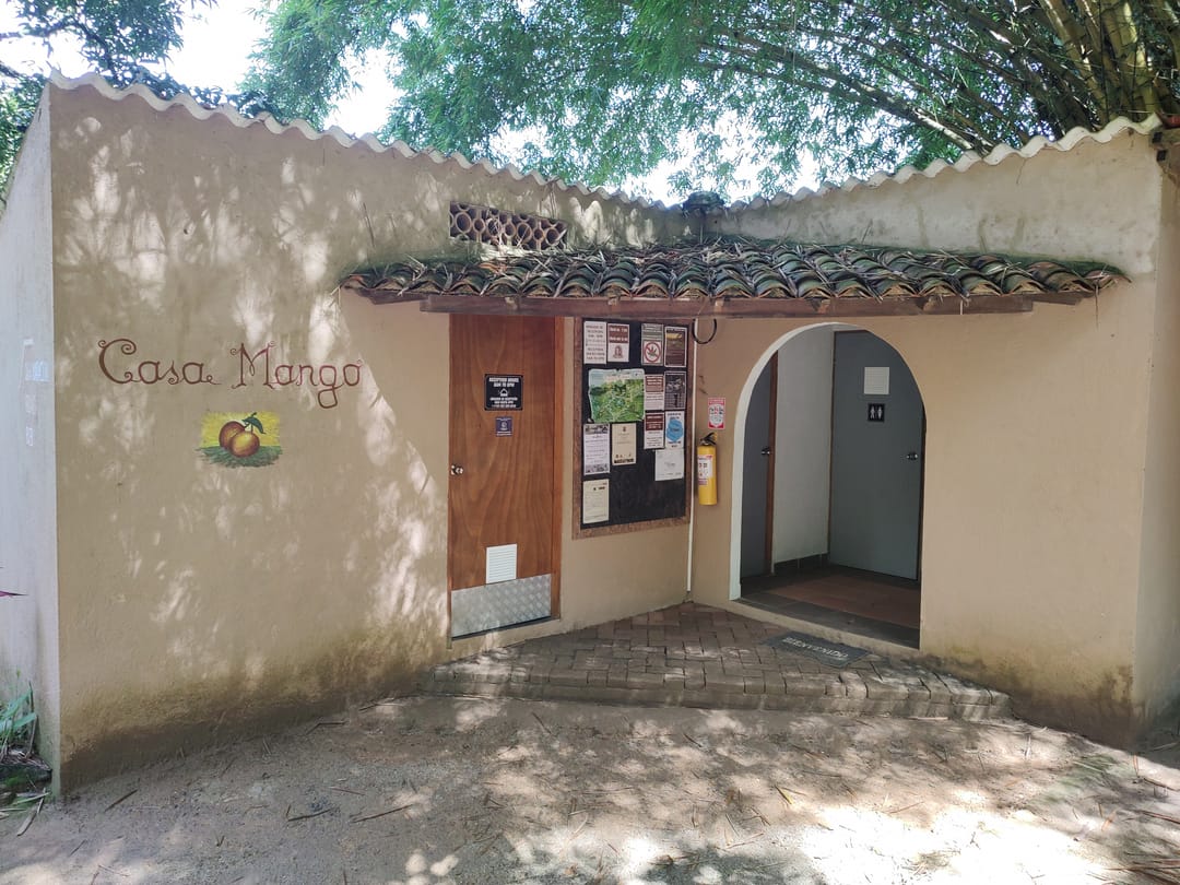 Fachada de Casa Mango con su nombre pintado en la pared, puerta en arco y techo de teja.