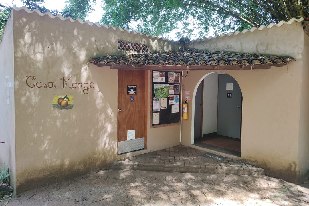 Fachada de Casa Mango con su nombre pintado en la pared, puerta en arco y techo de teja.