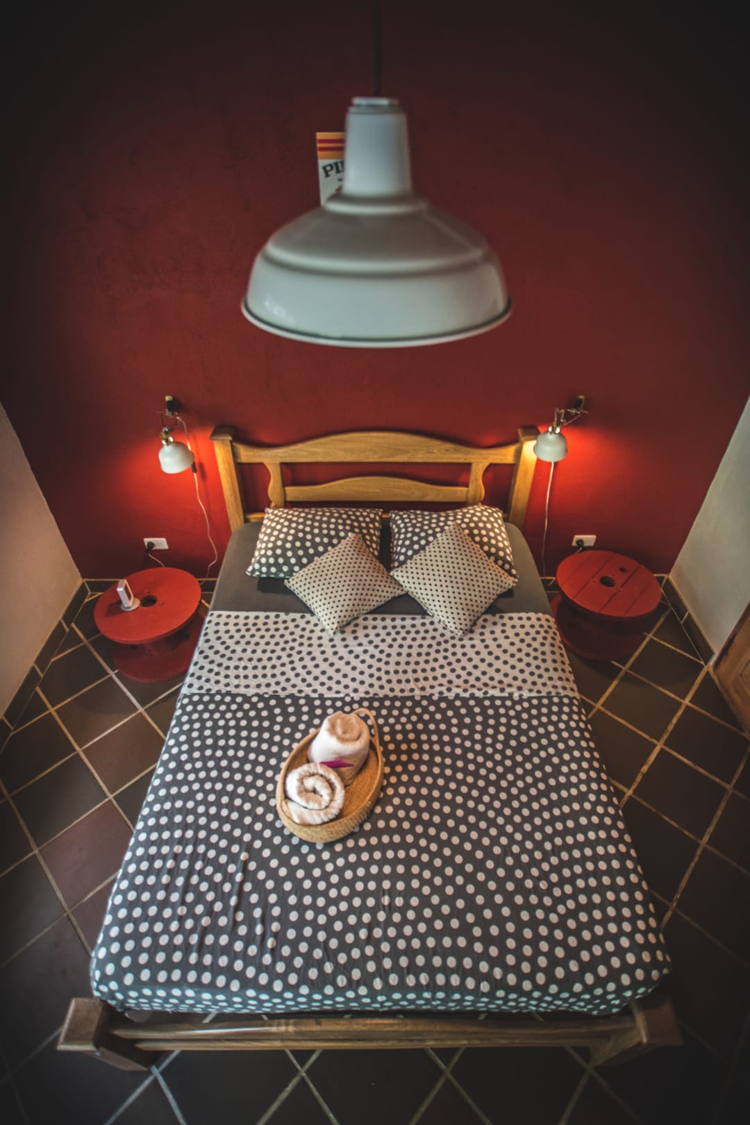 Habitación doble de Casa Maracuyá: pared roja, cama doble con colcha de puntos, lámparas de lectura y lámpara colgante.