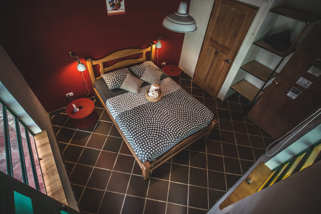 La habitación doble de pared roja vista hacia la puerta de madera y la ventana.