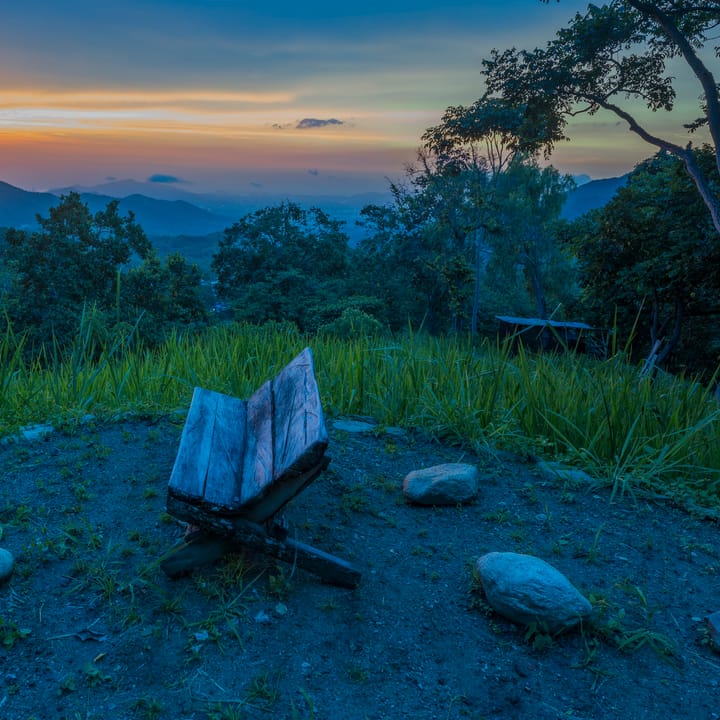 Un libro abierto sobre una roca del mirador a la hora azul, con las montañas y el último sol.