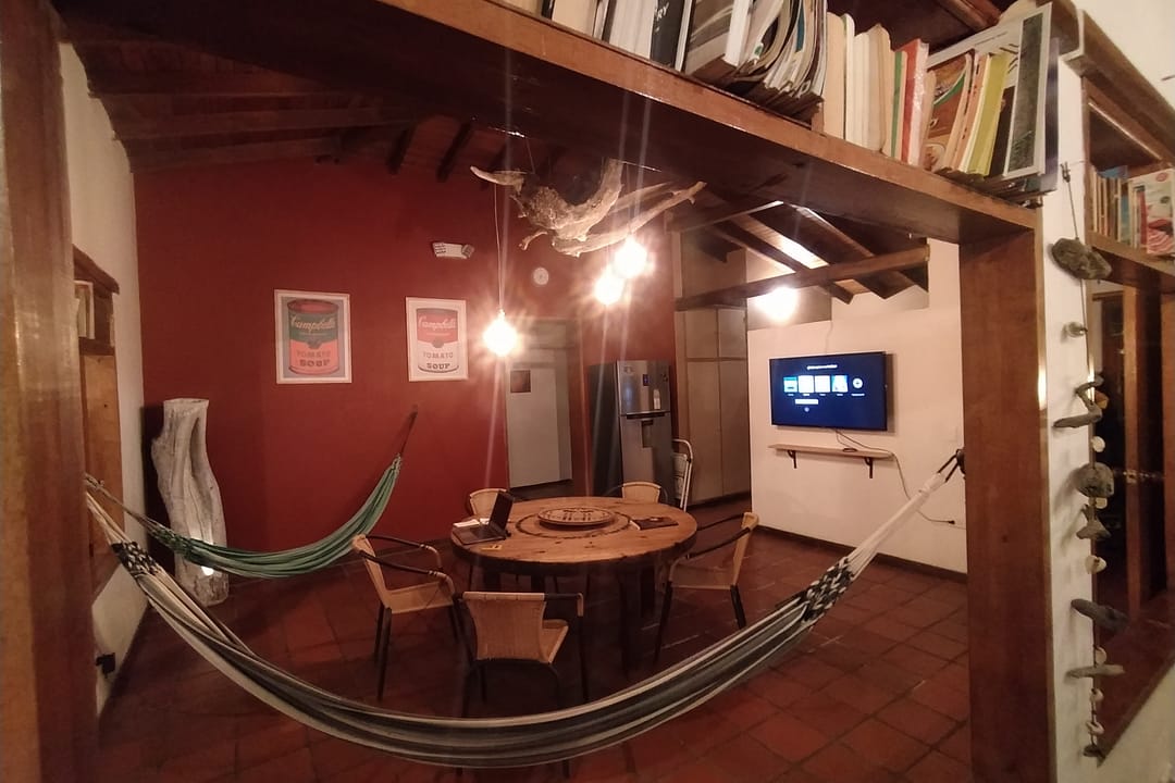Sala con pared roja, hamaca, mesa redonda de madera y televisor.
