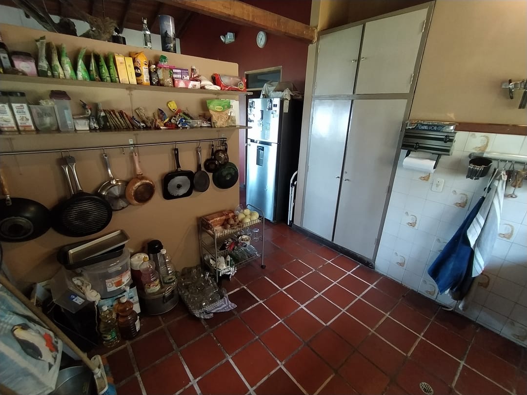 Cocina compartida de Casa Quinta con repisas llenas, ollas colgadas, nevera y piso de barro.