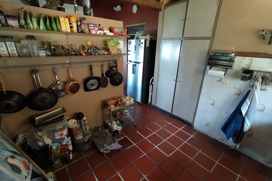Cocina compartida de Casa Quinta con repisas llenas, ollas colgadas, nevera y piso de barro.