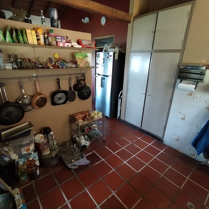 Cocina compartida de Casa Quinta con repisas llenas, ollas colgadas, nevera y piso de barro.